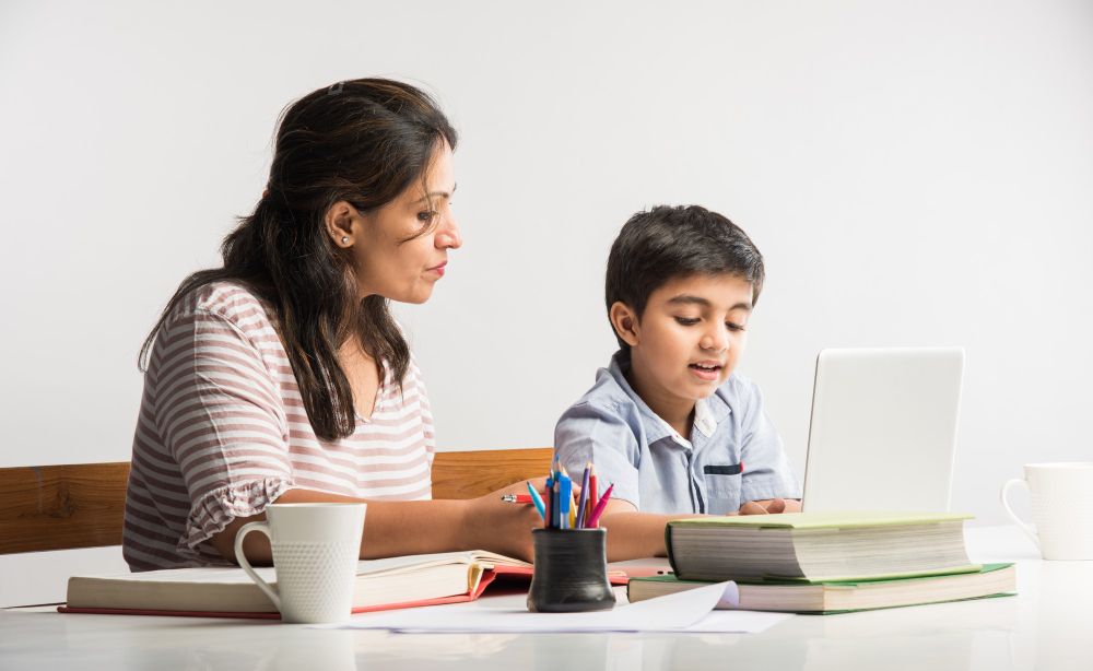 cute-indian-boy-with-mother-doing-homework-home-using-laptop-books-online-schooling-concept--2-