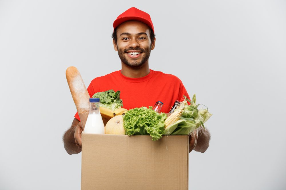 delivery-concept-handsome-african-american-delivery-man-carrying-package-box-grocery-food-drink-from-store-isolated-grey-studio-background-copy-space