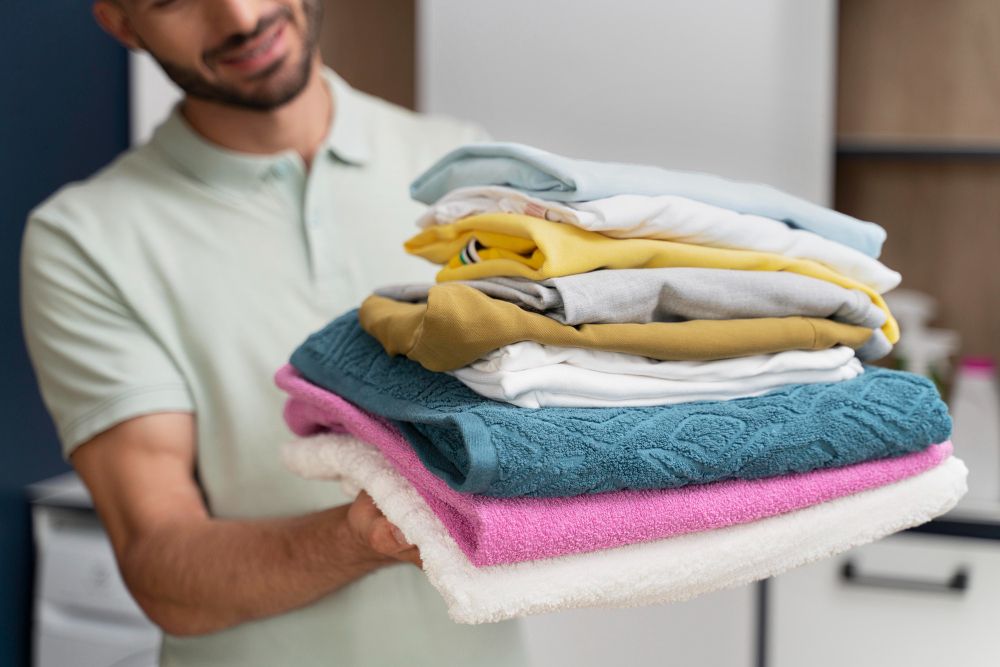 man-holding-pile-clean-clothes